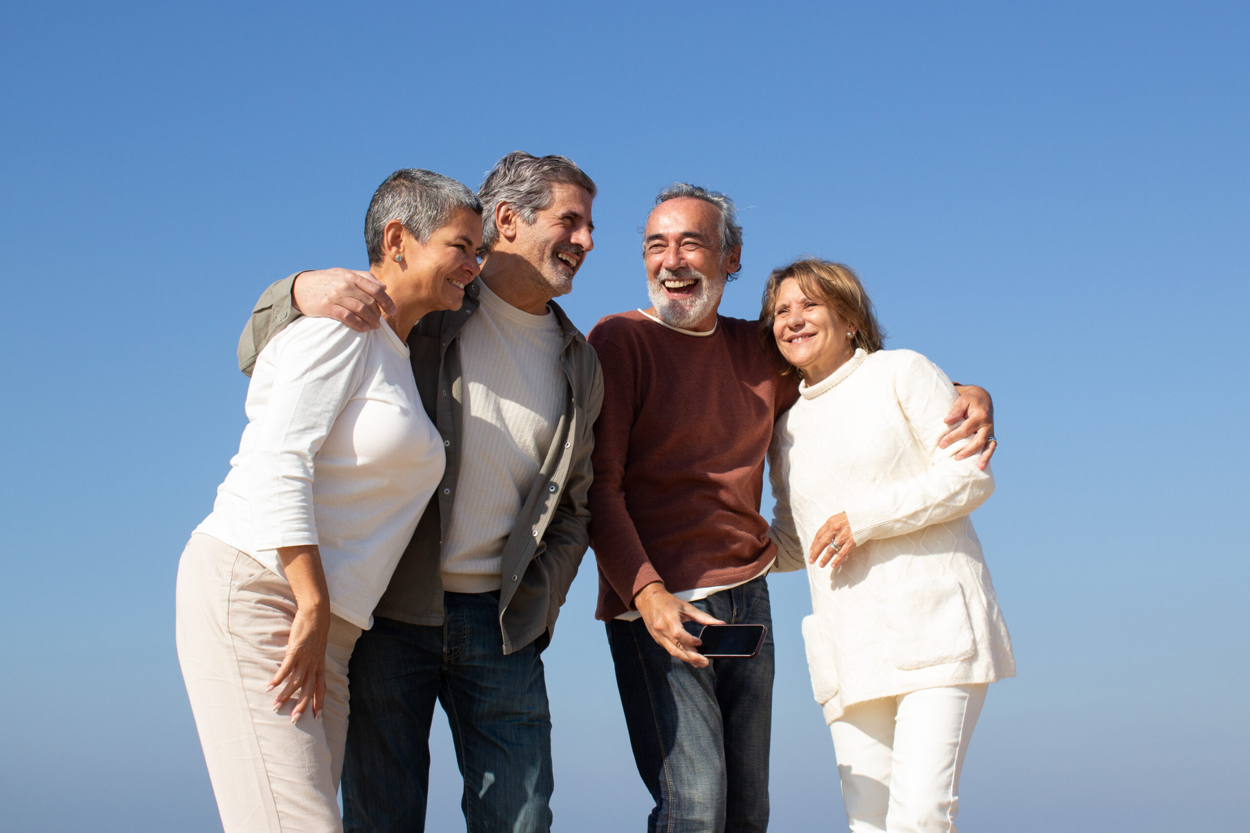 two senior couples having fun outdoors sunny day standing against blue sky laughing happy old friends enjoying leisure time together friendship leisure retirement concept scaled